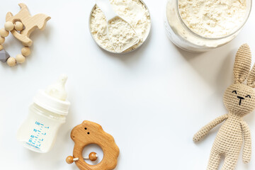 Milk for baby in a bottle with powdered milk in a spoon on white background, top view