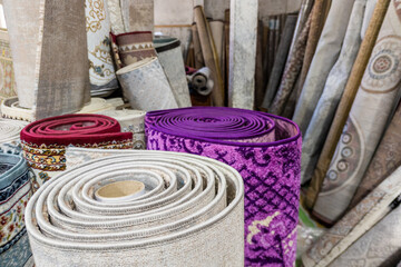 Many rolled carpets in Asian carpet store and carpet warehouse. Full-frame closeup background.