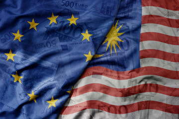 big waving realistic national colorful flag of european union and national flag of malaysia on a euro money banknotes background.