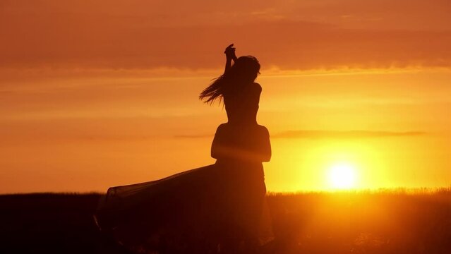 Silhouette of a couple in love against the background of a sunset in a field. Romantic scene of lovers. The concept of a love story, spending time together and feelings.