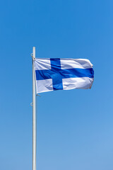 Fototapeta premium Finland flag attached to pole waving in the wind cloudless blue sky background
