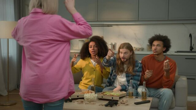 Group diversity multiracial friends women men guys girls together play game fun joy entertainment at home Caucasian woman showing pantomime gesticulate forms explaining object people trying guess word