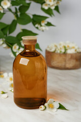 Composition with bottles of essential oil and beautiful jasmine flowers on a marble background. Side view. 