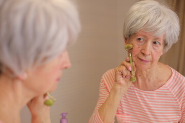 Mature female using marble roller to improve her skin health 