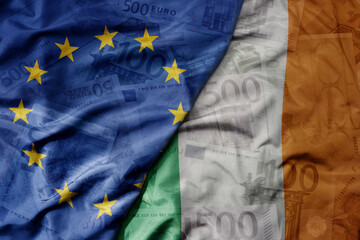 big waving realistic national colorful flag of european union and national flag of ireland on a euro money banknotes background.