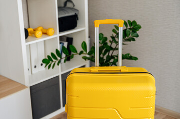 a yellow suitcase stands in the room waiting for a trip