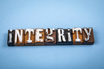 INTEGRITY. Wooden alphabet letter blocks on blue textured background