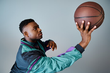 A fashionable young African American man in stylish attire holds a basketball. © LIGHTFIELD STUDIOS