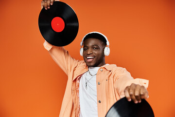 Young black man in stylish attire holding up a vinyl record.