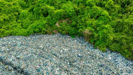 Obraz premium Aerial view, piles of garbage, plastic bottles and trash, and forests. Concept of waste disposal and separation to preserve the environment and save the planet.