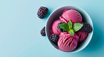 Bowl of blackberry ice cream scoops with fresh berries on pastel blue background, top view.