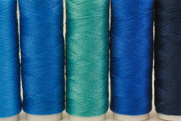 Several spools of thread lined up next to each other on a surface