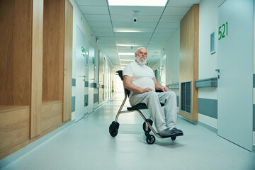 Old patient sits in a wheelchair in a hospital hallway