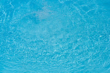 Blue water with ripples on the surface. Defocus blurred transparent blue colored clear calm water surface texture with splashes and bubbles. Water waves with shining pattern texture background.