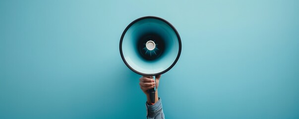Hand holding up a megaphone against a blue background for announcement concept