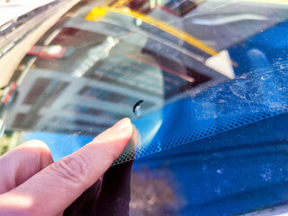 Close-Up of a Finger Pointing at a Chip on a Car Window in Daylight