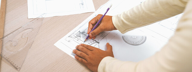 Cropped image of skilled architect designer hand draws blueprint with architectural equipment and...