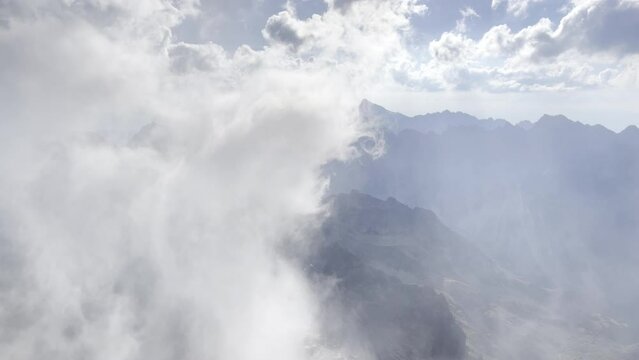 4K aerial footage of misty clouds rising up over Slovakian early morning in High Tatras mountain range with incredible Kriv&aacute;ň peak 2495m. Light and shadows playing. Rysy peak 2499m view.