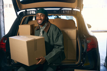 Man is sitting in the trunk of a car, holding a box in his hands
