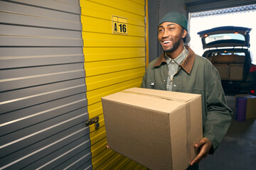 Young American male is holding a box in his hands in the storage service