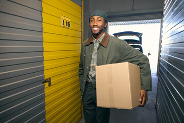 Happy American man is holding a box in his hands in the storage service