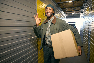 Young smiling man holds a box in his hands at a storage warehouse