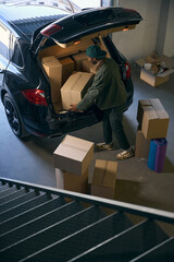 Young man takes boxes out of a car in a storage service