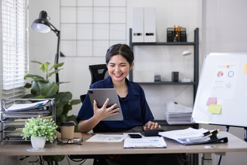 Young Asian woman using tablet in office workspace. Concept of business technology and productivity