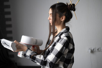 Young Woman in Checkered Shirt Holding a Cordless Vacuum Cleaner at home
