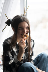 Young Girl Enjoying and biting a Delicious Cookie by the Window on a Sunny Afternoon