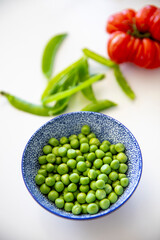 Recette de petits pois verts frais sur la table d'une cuisine.