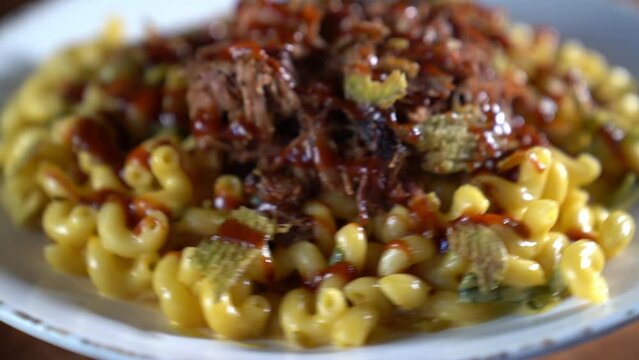 Closeup footage of a spinning plate of pulled pork with macaroni and cheese, with blur background