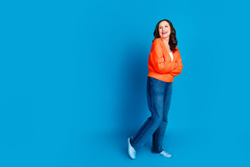 Full body photo of attractive senior woman crossed hands look empty space dressed stylish orange clothes isolated on blue color background