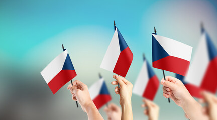 A group of people are holding small flags of Czech Republic in their hands.