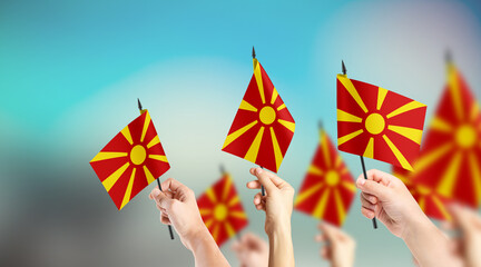 A group of people are holding small flags of Macedonia in their hands.