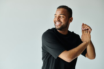 African American man in black shirt holding hands together.