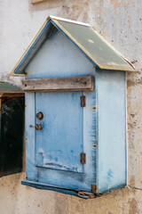 Une vieille boîte aux lettres en bois bleue en forme de maison sur un mur de béton