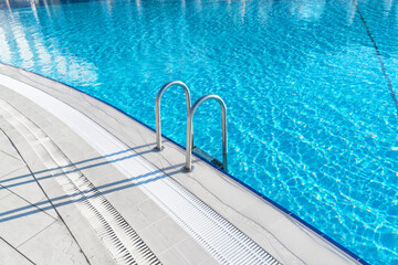 Obraz premium Swimming pool with stair and water. Swimming pool with handrail. Stainless steel ladder in pool. Grab bars ladder in the blue swimming pool