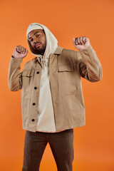 African American man in jacket and hoodie striking a pose against vibrant backdrop.