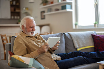 Closeup portrait of a smiling caucasian middle-aged mature man in glasses using digital tablet for...