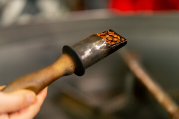 Close up of coffee holder in a roasting factory checking the roast level of the coffee ready to...