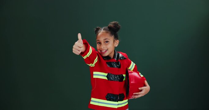 Face, firefighter and girl with thumbs up, smile and career ambition on dark studio background. Portrait, model or kid with uniform, child development or hand gesture for support, review or feedback