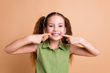 Photo of positive girl kid pointing teeth with index fingers isolated over pastel color background