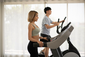 Young man and woman running on treadmills with curtain