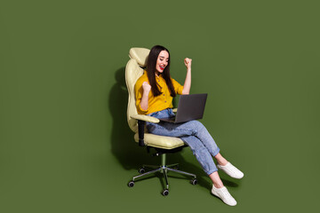 Full length photo of adorable lucky girl wear yellow shirt wining game modern gadget empty space isolated green color background