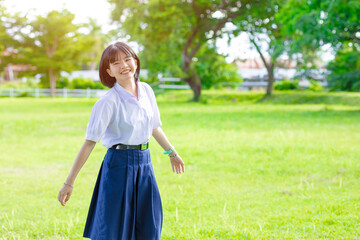 Portrait cute lovely happy Asian student school uniform girl in at green park outdoor