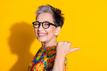 Photo of adorable lovely retired woman wear trendy print clothes offer empty space isolated on yellow color background