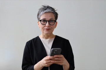 A senior woman happily uses her smartphone, embracing modern technology for communication and lifestyle.