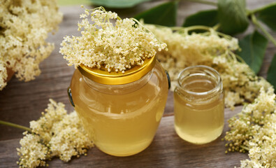Two glass jars of homemade elderberry flower syrup on a table