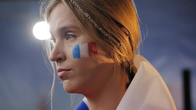 Sad France fan. Sad, upset woman fan of France with national flag on her shoulders, in shock. French sports fan depressed from defeat
